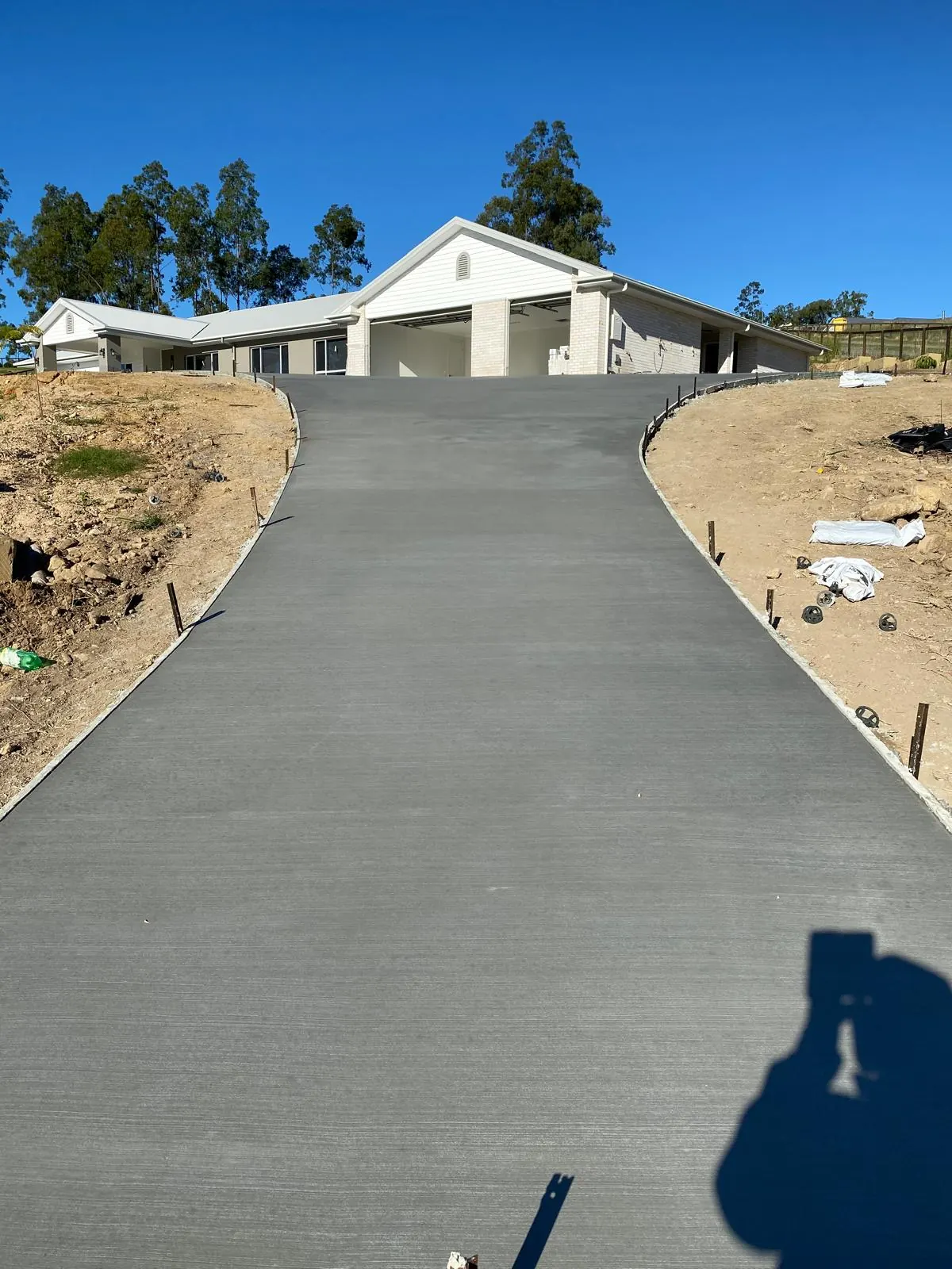 Curved broom-finish concrete driveway leading up to a triple garage