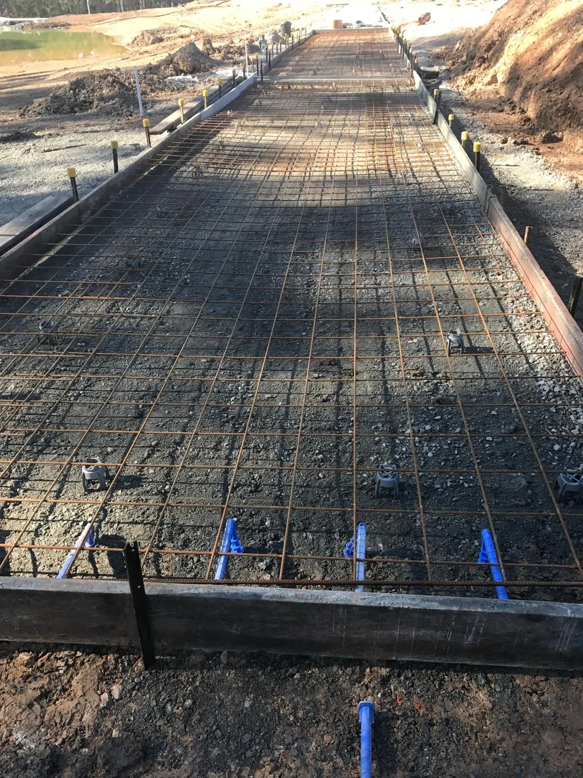Reinforced slab between screed rails beside a dam