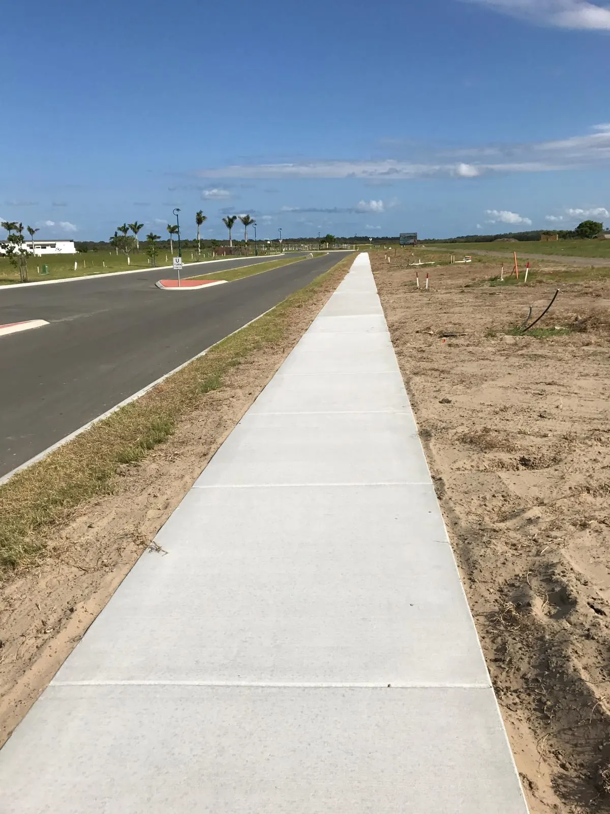 Subdivision footpath beside palms and a finished road